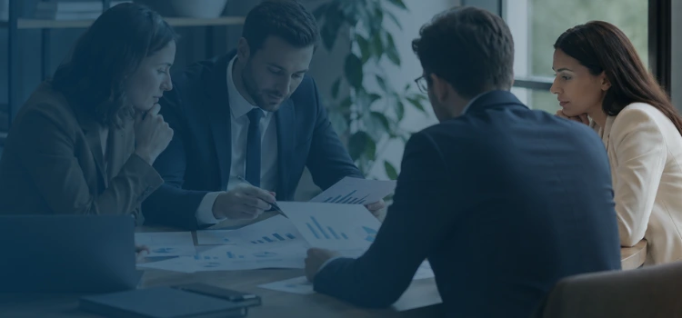 Business experts reviewing financial reports and EBITDA data during a Quality of Earnings analysis meeting.
