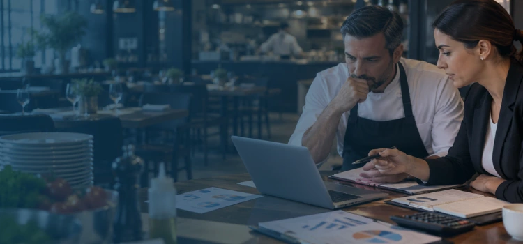 Restaurant owner and financial consultant reviewing cash flow reports and financial data inside a modern restaurant.